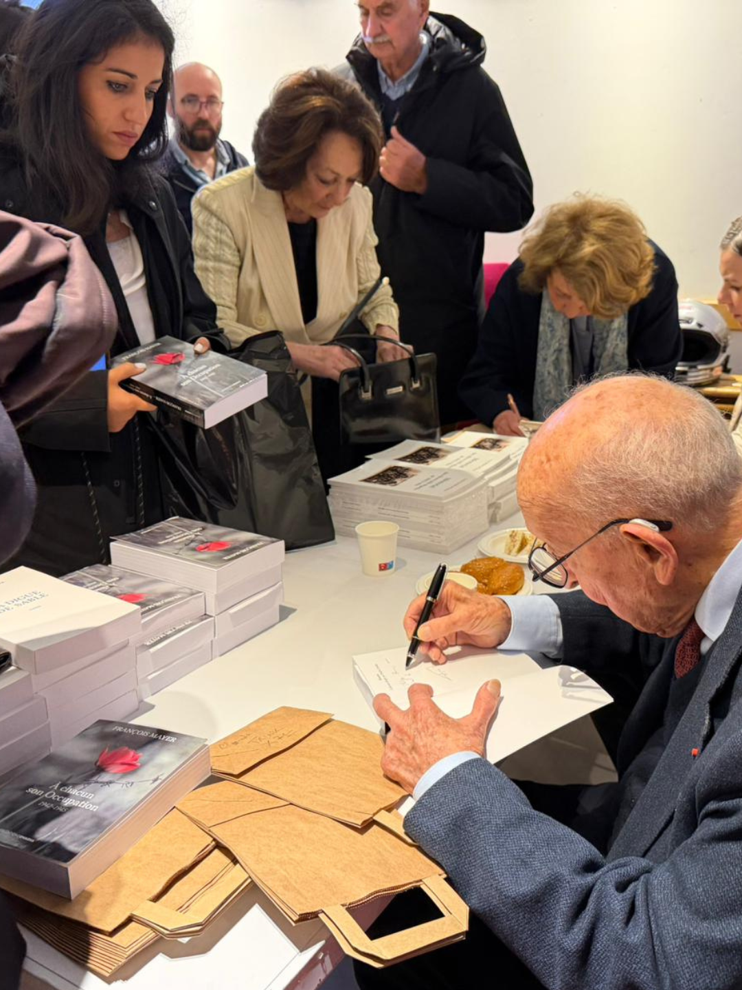 François Mayer signant des dédicaces de ses livres